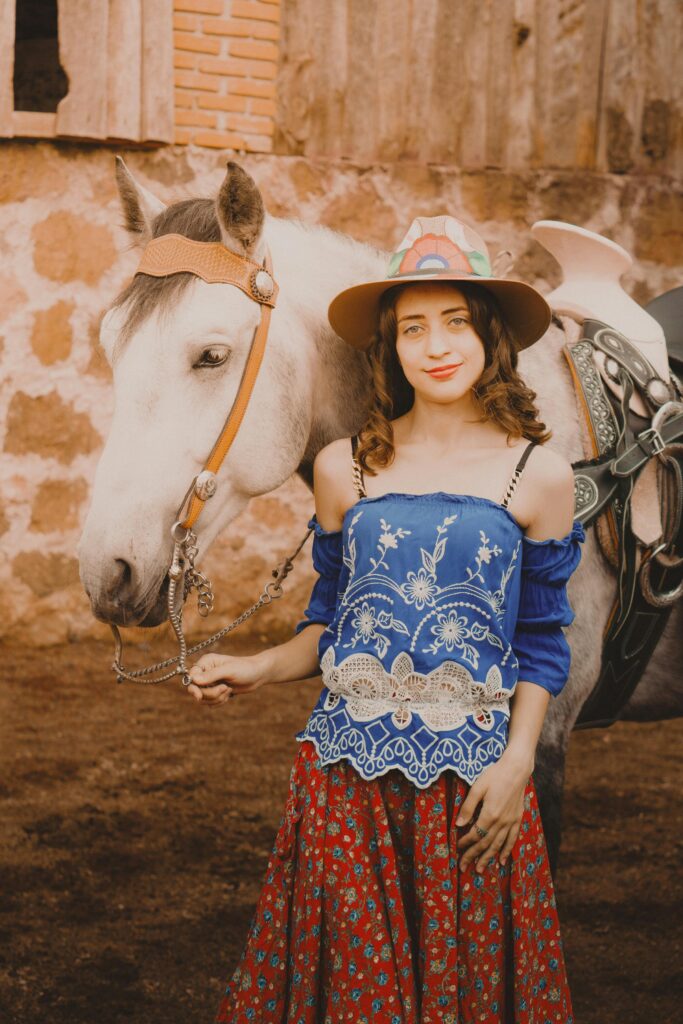 A Young Woman Wearing a Blouse and a Skirt Standing next to a Horse